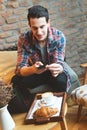 Young man sitting at a cafe, taking a snapshot of his food