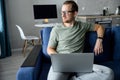 Young man sitting on the comfortable couch and using a laptop Royalty Free Stock Photo