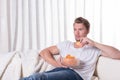 Young man sitting on couch and eating chips Royalty Free Stock Photo