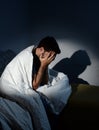 Young man sitting on couch at home wrapped in messy duvet suffering depression Royalty Free Stock Photo