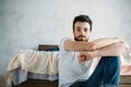 Young man sitting down on the floor near the bed Royalty Free Stock Photo