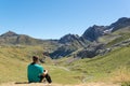 Young man sitting down and looking at a valley in Pyrenees.