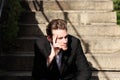 Young man sitting down outside wondering Royalty Free Stock Photo