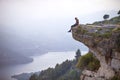 Young man sitting on edge of cliff and looking at river