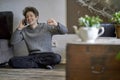 Young man sitting on the floor of his apartment laughing while calling with a mobile phone Royalty Free Stock Photo