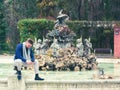 Young man sitting in the fountain of a park looking at his cell phone Royalty Free Stock Photo