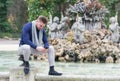 Young man sitting in the fountain of a park looking at his cell phone Royalty Free Stock Photo