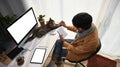 Young man sitting in front of computer with his cat and holding notebook. Royalty Free Stock Photo