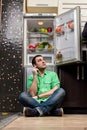 Young Man Sitting In Front Of Fridge Royalty Free Stock Photo