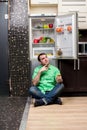 Young Man Sitting In Front Of Fridge Royalty Free Stock Photo