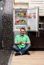 Young Man Sitting In Front Of Fridge Royalty Free Stock Photo