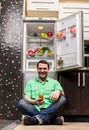 Young Man Sitting In Front Of Fridge Royalty Free Stock Photo