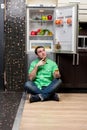 Young Man Sitting In Front Of Fridge Royalty Free Stock Photo