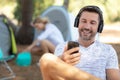 young man sitting in front tent listening to music