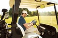 Young man sitting in a golf cart with a tablet Royalty Free Stock Photo