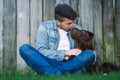 Young man sitting on the grass and kissing his beautiful dog Royalty Free Stock Photo