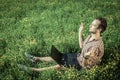 Young man sitting on the grass and meditating. Laptop on his knees. Royalty Free Stock Photo