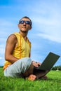 Young man sitting on the grass and working with laptop Royalty Free Stock Photo