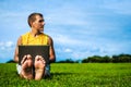 Young man sitting on the grass and working with laptop Royalty Free Stock Photo