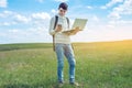 Young man sitting on a green meadow with laptop and using the phone on the background of blue cloudy sky Royalty Free Stock Photo