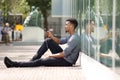 Young man sitting on ground listening to music on smart phone