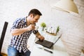 Young man sitting on kitchen desk at home and using laptop and drinking coffee Royalty Free Stock Photo