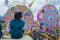 Young man sitting looking at the giant kites with animal figures flowers the cemetery,