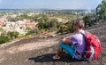 Young man is sitting on a mountain and looking on the town