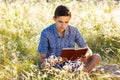 Young man sitting in nature reading a book Royalty Free Stock Photo