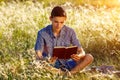 Young man sitting in nature reading a book Royalty Free Stock Photo