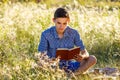 Young man sitting in nature reading a book Royalty Free Stock Photo