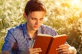 Young man sitting in nature reading a book Royalty Free Stock Photo