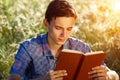 Young man sitting in nature reading a book Royalty Free Stock Photo