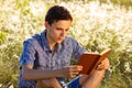 Young man sitting in nature reading a book Royalty Free Stock Photo