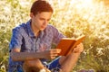 Young man sitting in nature reading a book Royalty Free Stock Photo