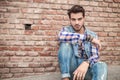 Young man sitting near a brick wall, resting Royalty Free Stock Photo