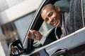 Young man sitting in new car looking out from window with key looking camera playful Royalty Free Stock Photo