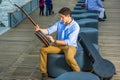 Young Man sitting outdoor, tuning strings of a banjo Royalty Free Stock Photo