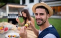 Young man sitting outdoors in back yard on garden barbecue, eating. Royalty Free Stock Photo