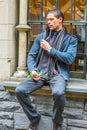 Young man sitting outdoors by window in winter, thinking Royalty Free Stock Photo