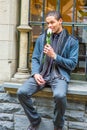 Young man sitting outdoors by window in winter, thinking Royalty Free Stock Photo