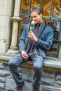 Young man sitting outdoors by window in winter, thinking Royalty Free Stock Photo