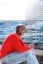 Young man sitting outside with mobile phone and laughing Royalty Free Stock Photo