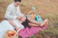 Young man sitting on picnic blanket with his girlfriend and playing guitar Royalty Free Stock Photo