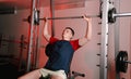 A young man sitting raises a barbell in the gym during a chest workout Royalty Free Stock Photo