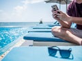 Young man sitting  resting and using smart phone at the swimming pool. Summer holiday traveling concept design banner with Royalty Free Stock Photo