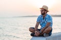 Young man sitting by the sea in sunset Royalty Free Stock Photo