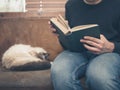 Young man sitting on sofa with cat is reading Royalty Free Stock Photo