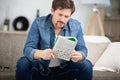 Young man sitting on sofa and doing crossword puzzle Royalty Free Stock Photo