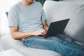 Young man sitting on the sofa at home typing on the laptop keyboard for online working, using internet, freelancer, relaxed,